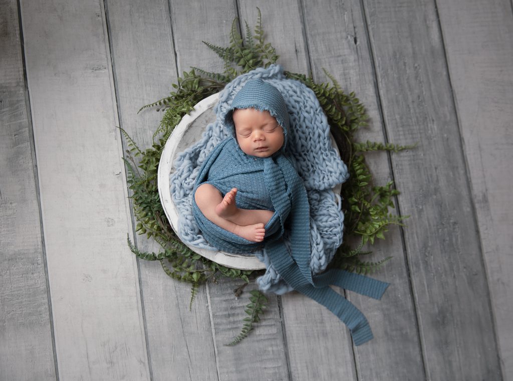 Peaceful baby in bowl wearing bonnet – posed newborn session