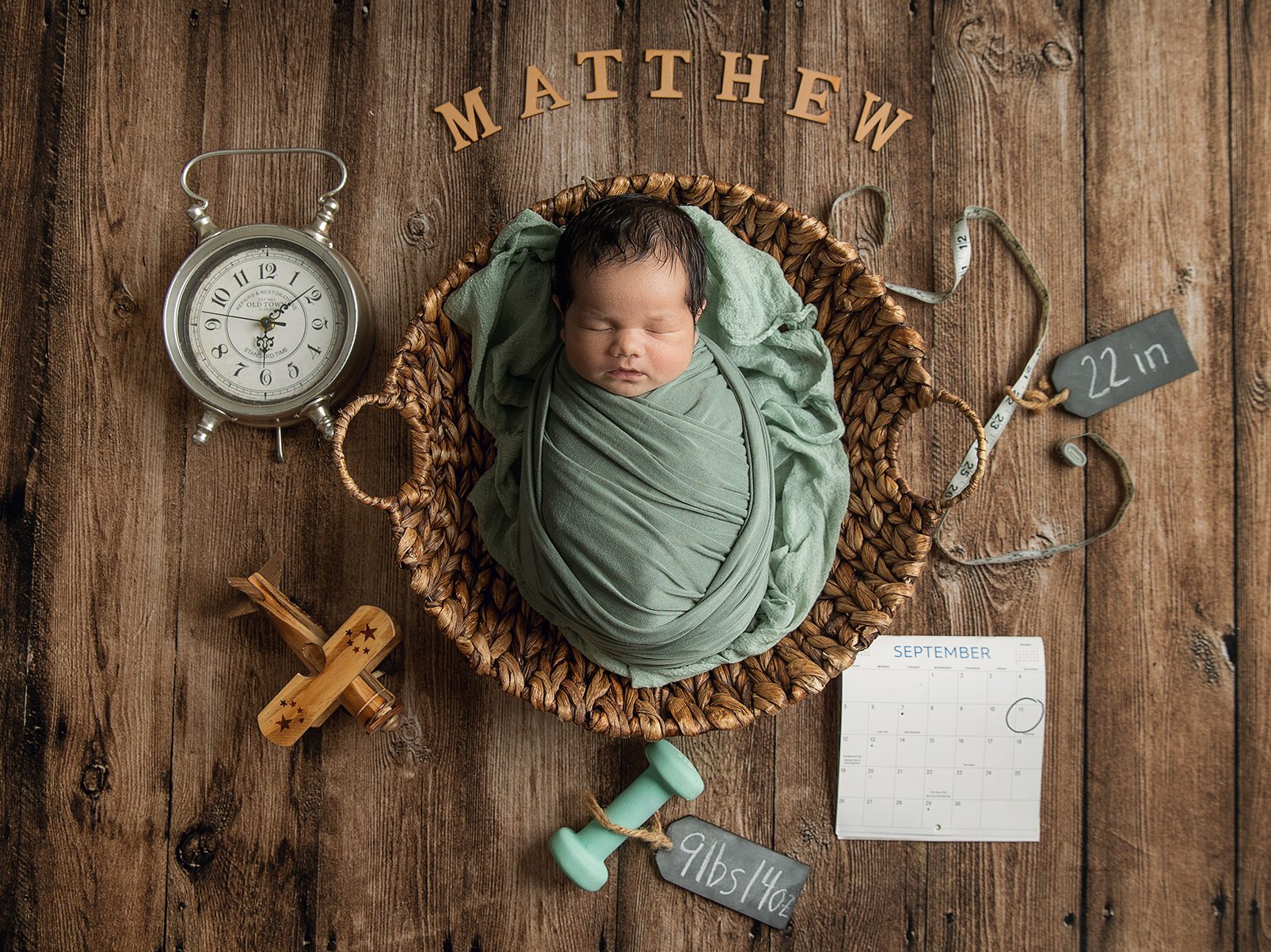 Newborn photos flatlay statistics, with baby name, weight, length, date and time on a wood backdrop