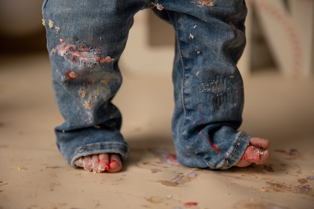 Close-up of icing-covered baby feet after a joyful first birthday cake smash session.