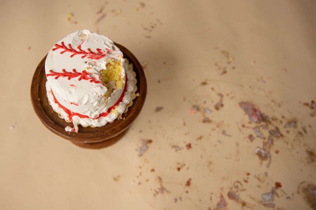 remnants of a baseball smash cake from rookie of the year first birthday photoshoot on tan backdrop